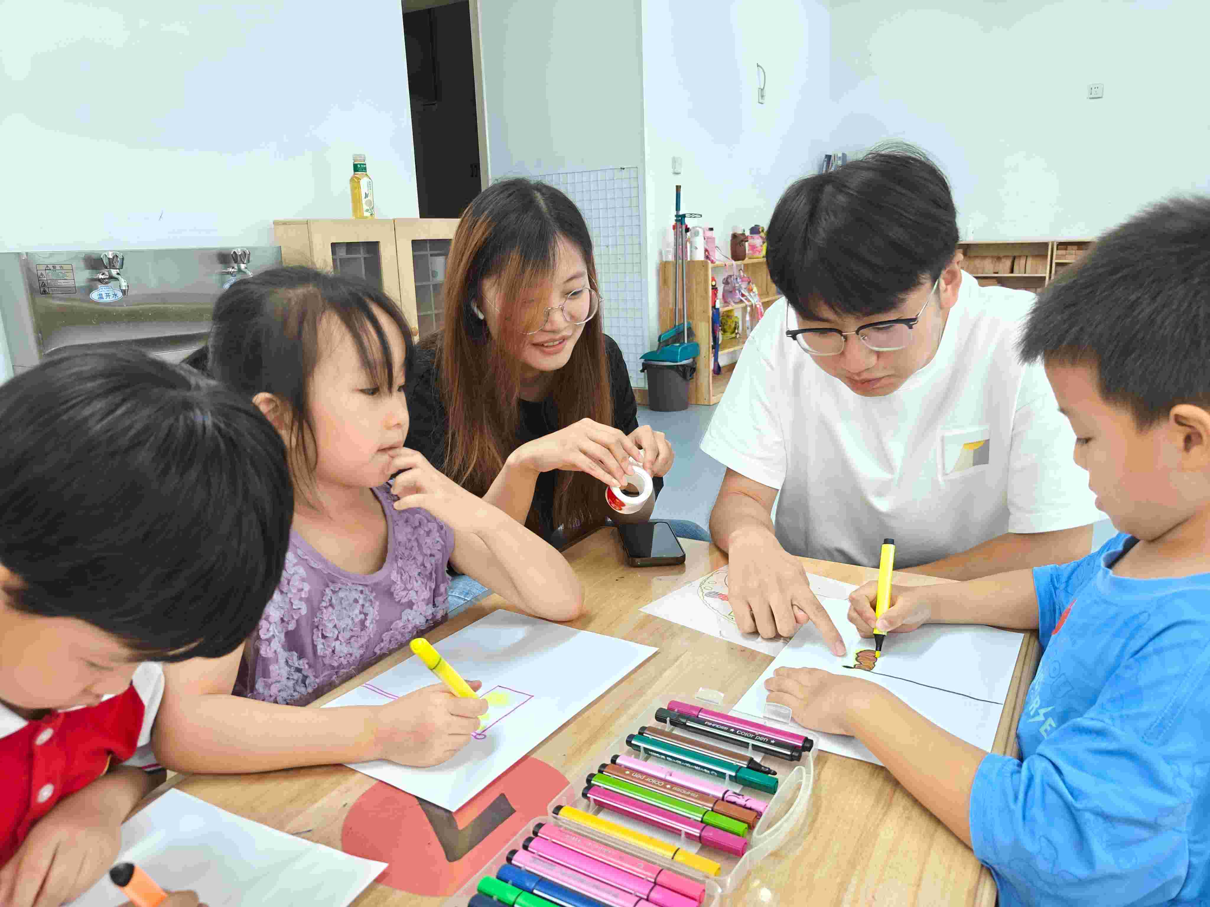 圖為實踐團成員宋立豪、譚依然在協(xié)助小朋友們完成畫作